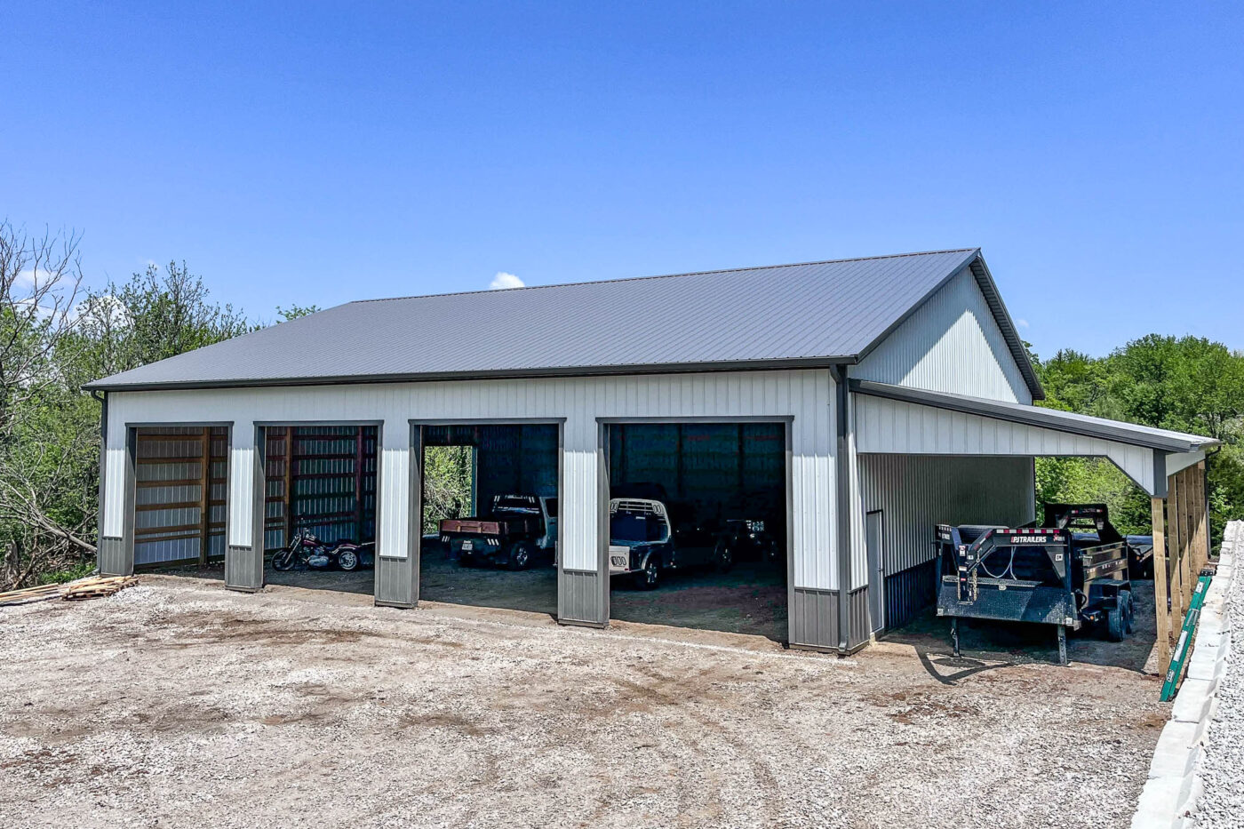 Large white metal building with new 6-inch Tuxedo Gray gutters installed along the roofline in Oak Grove, Missouri.