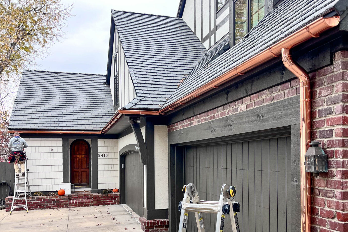 Front entry and garage area featuring copper gutters along steep rooflines on a house in Leawood, KS