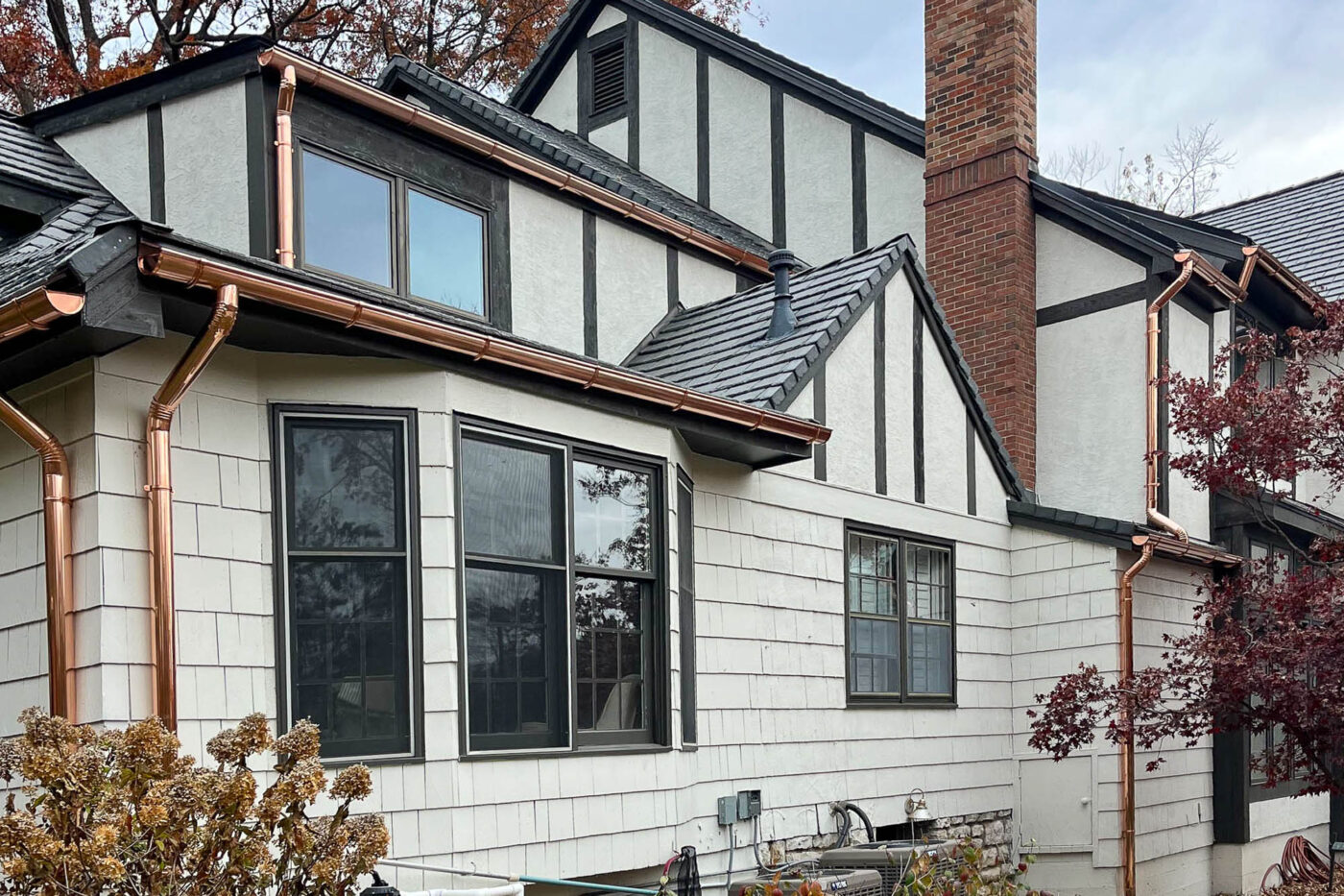 Tudor-style home with newly installed copper gutters and downspouts along upper and lower rooflines in Leawood KS