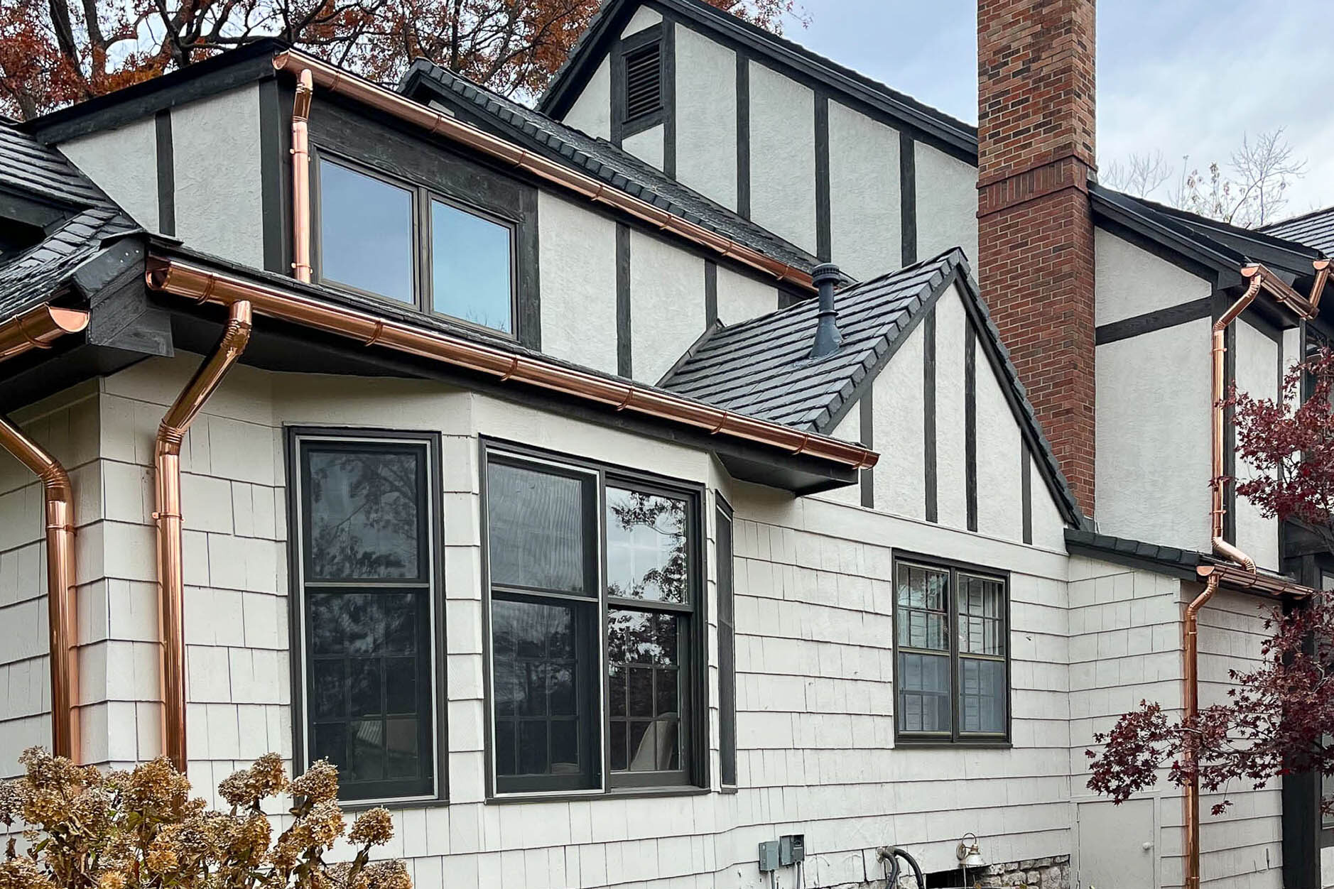 Tudor-style home with newly installed copper gutters and downspouts along upper and lower rooflines in Leawood KS