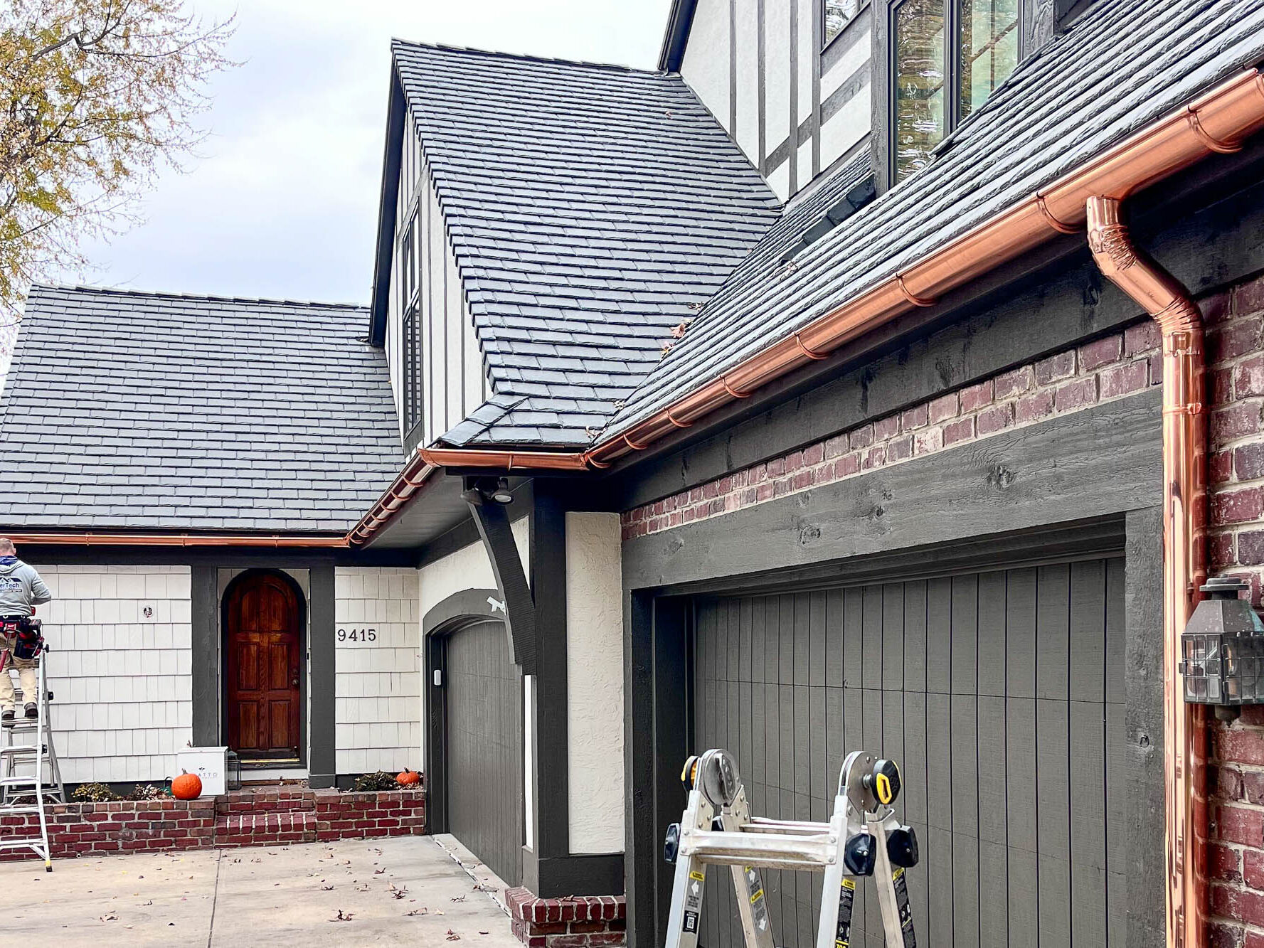 Front entry and garage area featuring copper gutters along steep rooflines on a house in Leawood, KS