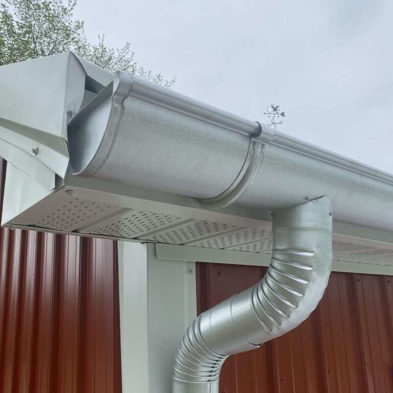 White gutter and downspout at the corner of a red barn in Grain Valley, MO